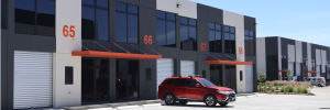 Row of industrial units with bay numbers 65 to 68 orange awnings and a red suv in the foreground