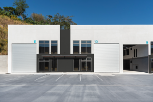 Fachada de ofibodegas modernas de deconsa guatemala con portones industriales y área de estacionamiento