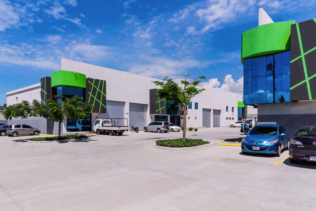 Modern commercial building with lime green and black geometric facade glass windows and a spacious parking lot under a blue sky